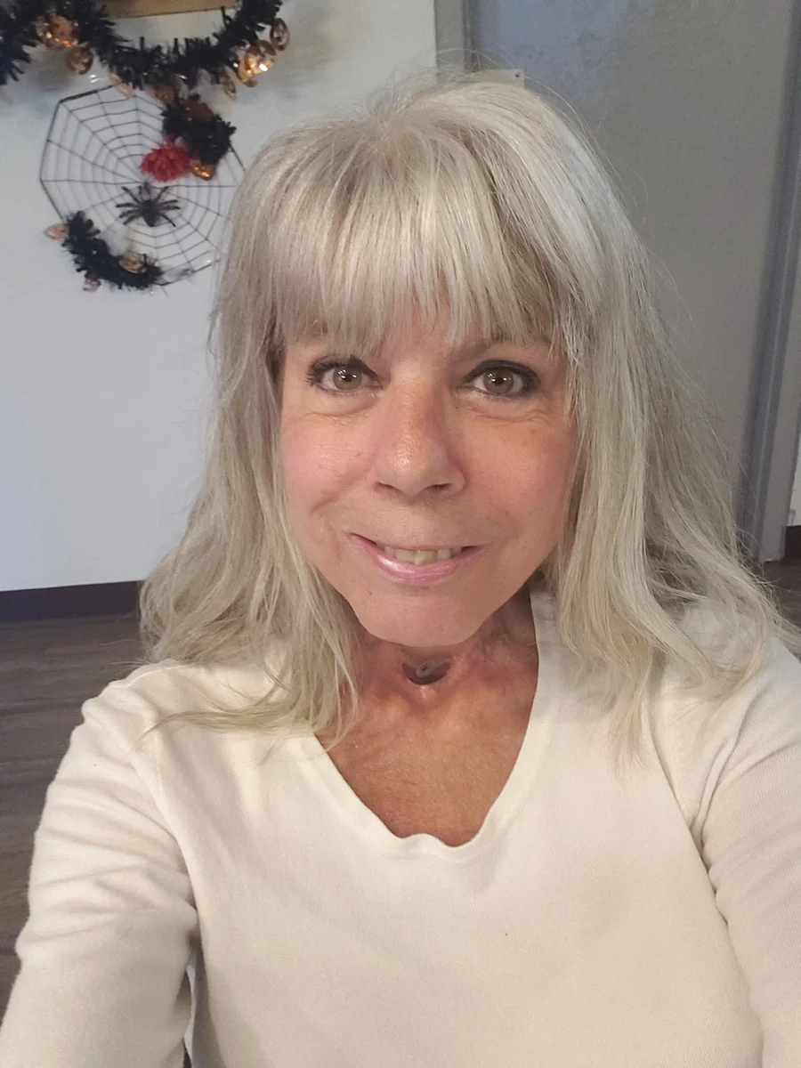 Vivienne smiling at the camera, wearing a white top.